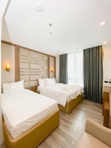 a hotel room with two beds and a couch at El Vistra Hotel Angeles in Angeles