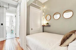a white bedroom with two mirrors on the wall at Downtown at the Derenne in Savannah +46 photos