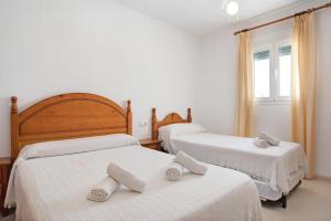 a bedroom with two beds with white sheets at Almadraba 2 - Andalmar in Conil de la Frontera