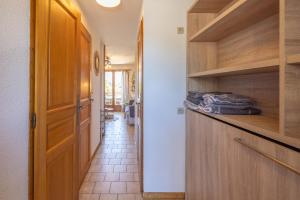a kitchen with wooden cabinets and a hallway at Le Morylan - Immoclean in Morillon
