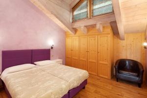a bedroom with a purple bed and a black chair at Chalet Picchio Trilocale in Livigno