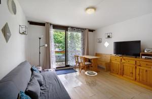 un salon avec un canapé et une télévision à écran plat dans l'établissement Au Pied Des Pistes Le Corbier 73, à Villarembert