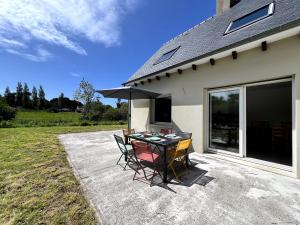 un patio avec une table, des chaises et un parasol dans l'établissement Maison De Charlie Madame est servie, à Trégastel