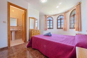 a bedroom with a pink bed and a bathroom at Vila Tres Cales in Les tres Cales