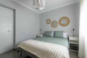 ein weißes Schlafzimmer mit einem Bett und einem Spiegel in der Unterkunft Málaga Dream Apartment in Málaga