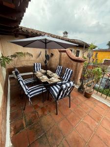 a table with chairs and an umbrella on a patio at Cozy Loft & Terrace in Antigua in Antigua Guatemala