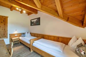 two beds in a room with wooden ceilings at Stoffnerhof Apt Edelweiß in Tesido