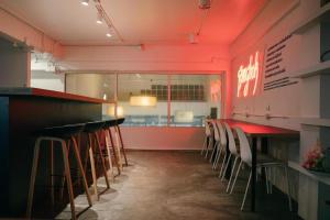 a bar with stools in a restaurant with red lighting at Qilombo Hostel Silom in Bangkok
