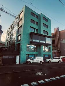 two cars parked in front of a green building at Apartmenthaus MK Immobilien in Stuttgart