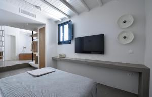 a bedroom with a bed and a tv on the wall at ANOTERRA VILLAS -Anassa in Ambelas