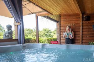 a woman reading a book next to a swimming pool at Chalet avec jacuzzi privatif in Fichous-Riumayou