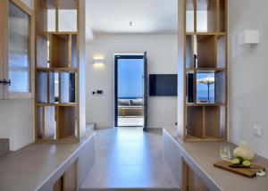 a kitchen with wooden cabinets and a hallway with an open door at ANOTERRA VILLAS -Anassa in Ambelas