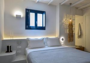 a bedroom with a bed with white sheets and a window at ANOTERRA VILLAS -Anassa in Ambelas +57 photos