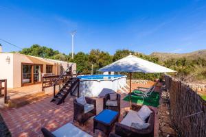 een patio met een zwembad, stoelen en een parasol bij Apartment Tina Capdepera in Capdepera