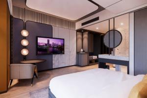 ein Hotelzimmer mit einem Bett und einem Fernseher an der Wand in der Unterkunft Nusatu by ARTOTEL - Semarang in Semarang