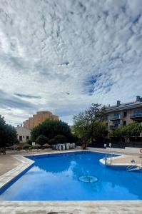 une grande piscine bleue avec un ciel nuageux dans l'établissement BenalBacko, Apartment in Arroyo de la Miel, Benalmádena, à Benalmádena