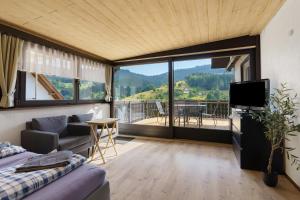 a living room with a couch and a tv and a balcony at Ferienwohnung am Braunberg in Oppenau