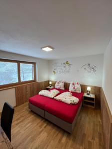 a bedroom with two beds with red sheets and pillows at Töniglerhof Apt Abendrot in Trodena