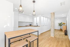 eine Küche mit weißen Schränken, einem Holztisch und Bänken in der Unterkunft Sunflower Avenida in Santa Pola