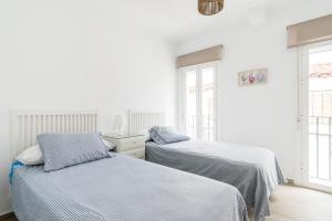 two beds in a room with white walls and windows at Apartamento La Bonita in Conil de la Frontera