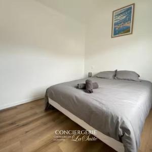 una cama en un dormitorio con paredes blancas y suelo de madera en L'impasse, en Cherbourg-en-Cotentin