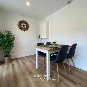 Una mesa de comedor con sillas y un reloj en la pared. en L'impasse, en Cherbourg-en-Cotentin 14 fotos más