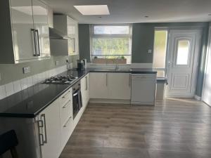 a kitchen with white cabinets and black counter tops at Spacious 2 & 3 Bed Ribble Valley Apartments in Blackburn +7 photos