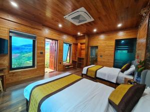 two beds in a room with wooden walls at Kovie Hoa Lac Xanh Resort in Nam Giao