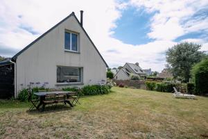 a white house with a picnic table in the yard at Maison Familiale Kerlaho - Vue Mer in Trébeurden