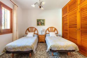 a bedroom with two beds and a wooden cabinet at S'hort des Baladres Ibiza Villa in Santa Eularia des Riu +25 photos