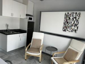 a kitchen with two chairs and a white board at Atico playa de Rota in Rota