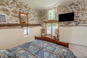 a bedroom with a bed and a flat screen tv at Gite du moulin - Ariège in Carla-de-Roquefort