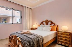 een slaapkamer met een bed en twee nachtkastjes en een raam bij Costamar Arinaga in Arinaga