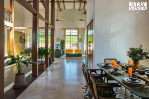 a dining room with a long table and chairs at StayVista's Rustique Radiance - Hillside Retreat with Outdoor Pool & South Indian Architecture in Khopoli