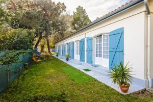 a building with blue doors and a yard at Longère proche plage et forêt in Saint-Trojan-les-Bains