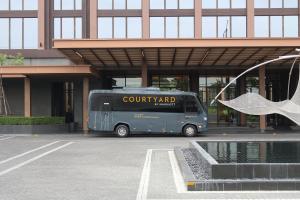 a blue bus parked in front of a building at Courtyard by Marriott Bangkok Suvarnabhumi Airport in Lat Krabang