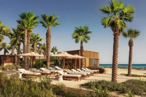a row of chairs and umbrellas on the beach at The Red Sea EDITION in Ḩanak
