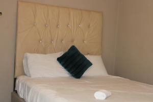a bed with a black pillow on top of it at Chic Guest House Alberton in Alberton