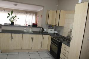 a kitchen with wooden cabinets and a black stove top oven at Chic Guest House Alberton in Alberton