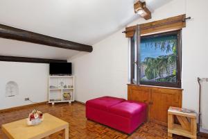 a living room with a red ottoman and a window at Maison Ninive in Aosta