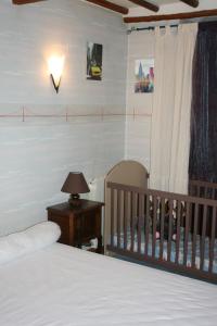 a bedroom with a bed and a crib and a lamp at La Maison de Yana in Saint-Marcel-dʼArdèche
