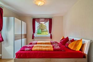 a bedroom with a red bed with a window at Mitterfelder Donaublick in Vilshofen an der Donau