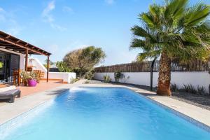 een zwembad in de achtertuin van een huis met een palmboom bij Casa Sultana in Playa Blanca