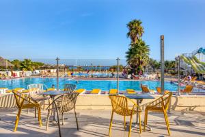 - un groupe de tables et de chaises à côté de la piscine dans l'établissement Mobilhome 530 - 8 personnes, à Lattes