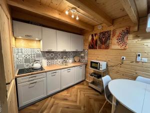 a kitchen with white cabinets and a table at Domek Prowansja Sosnówka Karpacz BALIA in Sosnówka