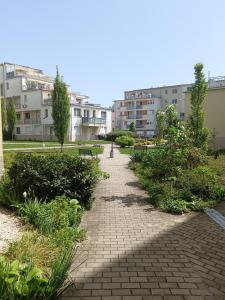 un chemin en briques dans un parc avec des bâtiments en arrière-plan dans l'établissement Local-Lux Apartman 3 szoba, privát parkoló, à Kecskemét