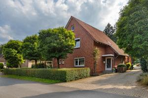 a red brick house with a tree in front of it at Ferienhaus In Oerrel Mit Pool in Faßberg