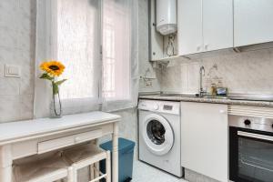 Una cocina con lavadora y un jarrón con un girasol. en Sunflower Tailandia_Santa Pola, en Santa Pola