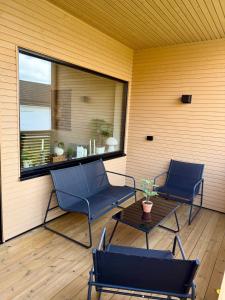 two chairs and a table on a porch with a window at New modern apartment in Sandefjord