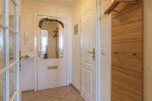 einen Flur mit einer weißen Tür und einem Spiegel in der Unterkunft Sylter Residenz Westerland in Westerland + 23 Fotos